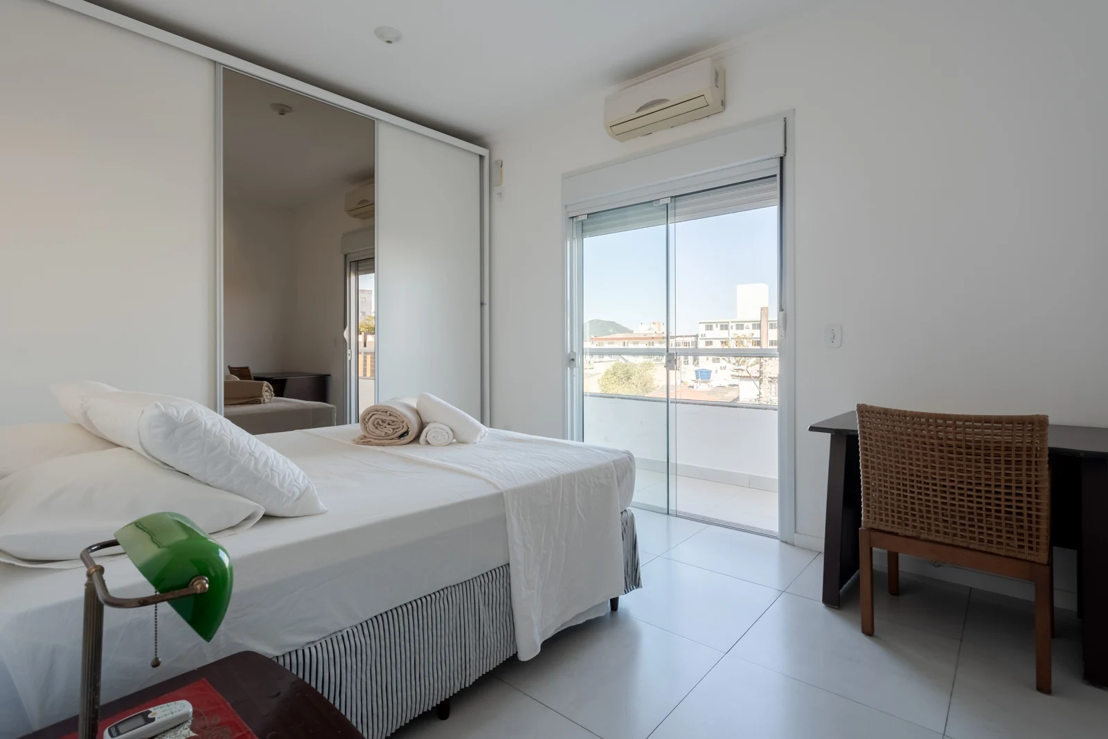 Quarto com cama queen, ar-condicionado, mesa de trabalho e acesso à varanda